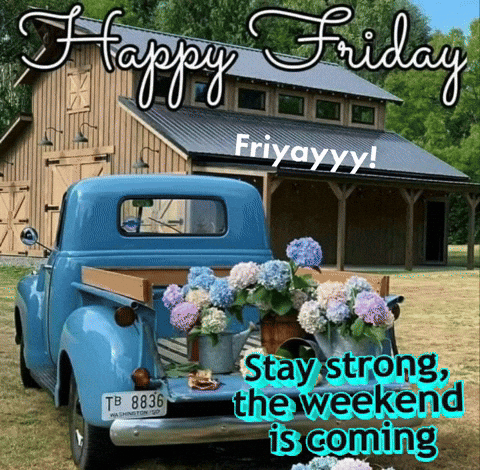 A Blue Truck Is Parked In Front Of A Barn With Flowers In The Back GIF