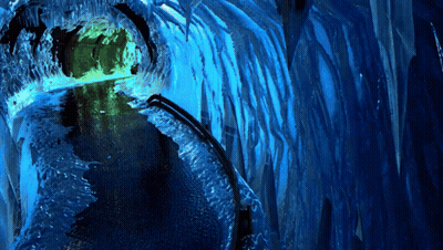 A Blue Tunnel With Icicles And A Green Light GIF