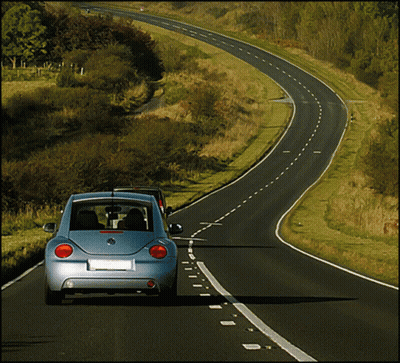 A Blue Volkswagen Beetle Is Driving Down A Road GIF