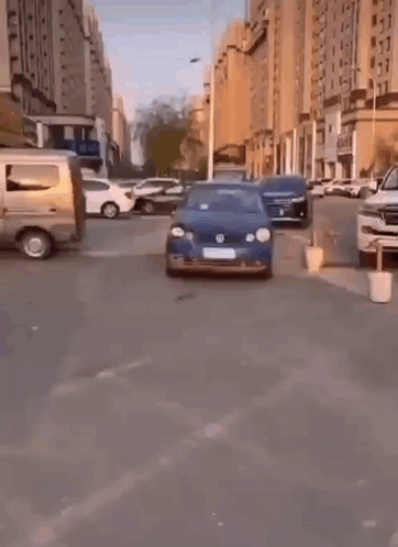 A Blue Volkswagen Car Is Parked On The Side Of A City Street . GIF