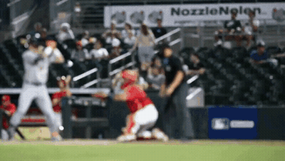 A Blurred Image Of A Baseball Game With A Nozzlenolen Sign In The Background GIF