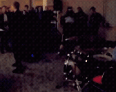 A Blurred Image Of A Man Playing Drums In A Dark Room GIF