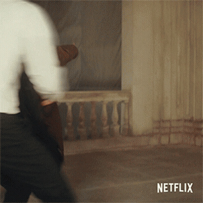 A Blurred Image Of A Man Walking With A Netflix Logo Behind Him GIF