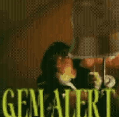 A Blurred Image Of A Person Holding A Lamp With The Word Gem Alert Written In Yellow GIF