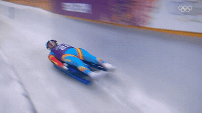 A Blurred Image Of A Person Sledding Down A Snowy Track With The Olympics Logo In The Background GIF
