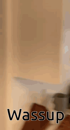 A Blurred Image Of A Person Standing Next To A Wall With The Word Wassup On It . GIF