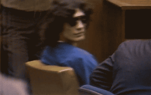 A Blurred Image Of A Person Wearing Sunglasses And A Blue Shirt GIF