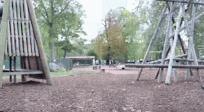 A Blurred Image Of A Playground In A Park With Trees In The Background GIF