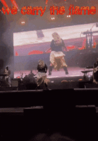 A Blurred Image Of A Stage With The Words We Carry The Flame GIF