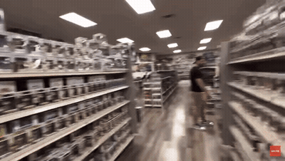 A Blurred Image Of A Store Aisle With A Red Arrow Pointing To The Bottom Left GIF