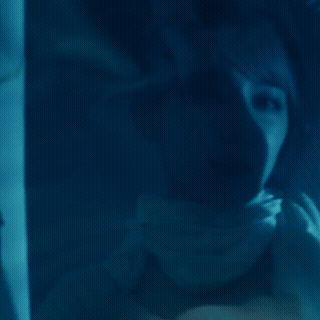A Blurred Image Of A Woman Behind A Blue Glass GIF