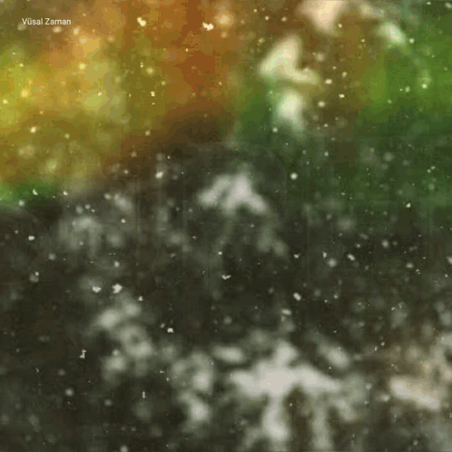 A Blurred Image Of Snow Falling With The Name Vusal Zaman In The Upper Right Corner GIF