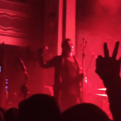 A Blurry Photo Of A Concert With Red Lights GIF