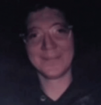 A Blurry Photo Of A Man Wearing Glasses And A Black Shirt GIF