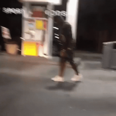 A Blurry Photo Of A Person Walking In Front Of A Store That Says Sports GIF