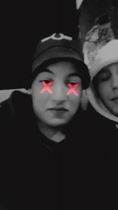A Blurry Photo Of Two People With A Red Smiley Face On Their Face GIF