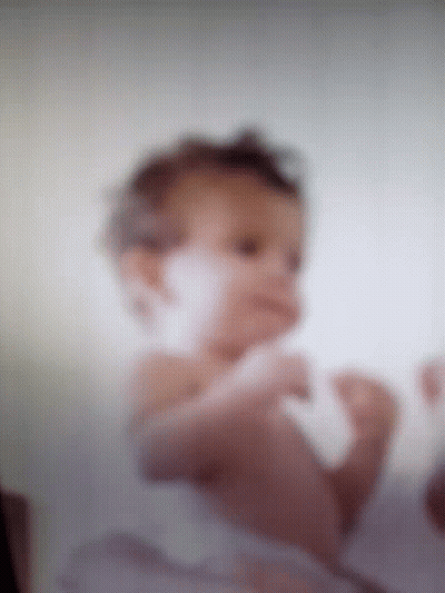 A Blurry Picture Of A Baby Laying On Its Stomach GIF