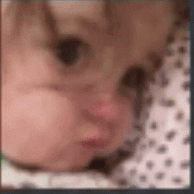 A Blurry Picture Of A Baby 'S Face With A Polka Dot Shirt . GIF