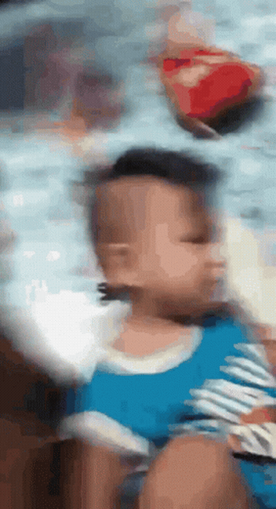 A Blurry Picture Of A Baby With A Blue Shirt On GIF