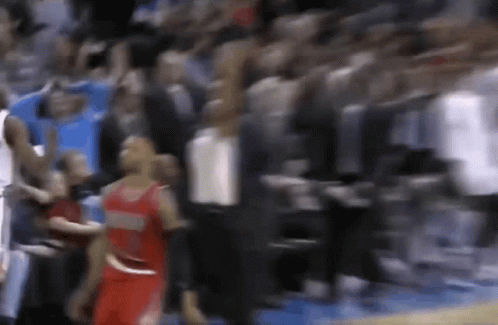 A Blurry Picture Of A Basketball Game With A Player In A Red Jersey Standing In Front Of A Crowd . GIF