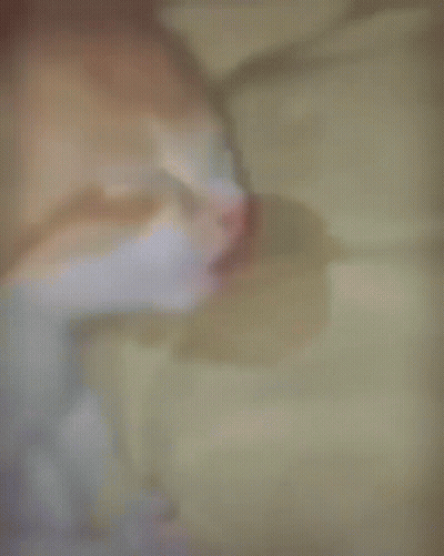 A Blurry Picture Of A Cat Sleeping On A Blanket GIF