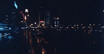 A Blurry Picture Of A City Street At Night With A Sign That Says ' No Smoking ' GIF