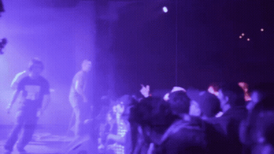 A Blurry Picture Of A Crowd At A Concert With Purple Lights Behind Them GIF