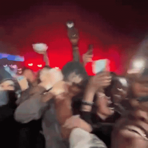 A Blurry Picture Of A Crowd Of People Dancing In A Dark Room GIF