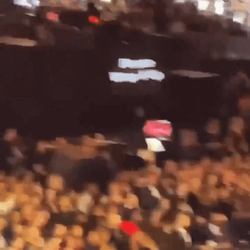 A Blurry Picture Of A Crowd With A Sign That Says " Exit " GIF