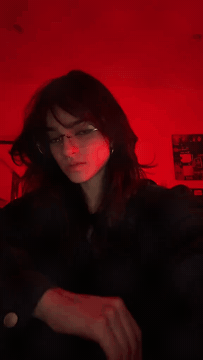 A Blurry Picture Of A Girl Wearing Glasses In Front Of A Red Background GIF