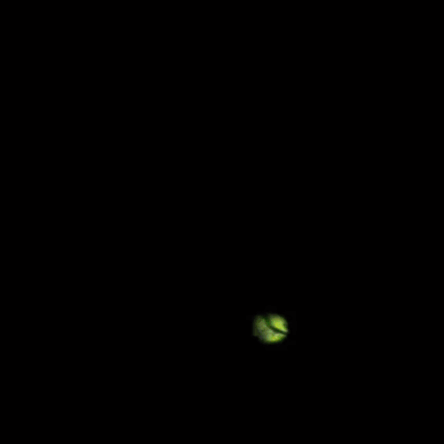 A Blurry Picture Of A Green And Yellow Object On A Dark Background GIF