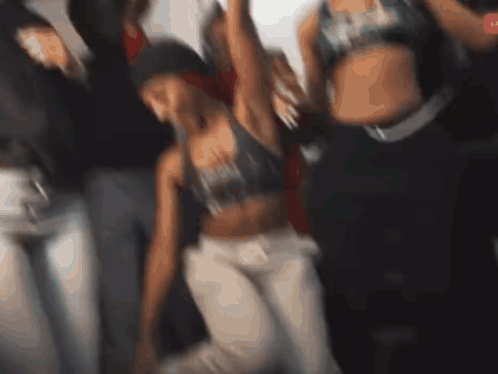 A Blurry Picture Of A Group Of People Dancing With One Woman Wearing A Sports Bra That Says ' Reebok ' On It GIF