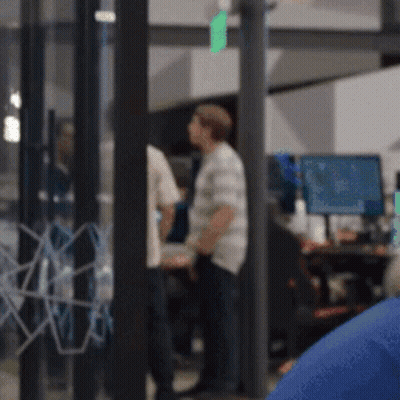 A Blurry Picture Of A Group Of People In A Room With Computers GIF