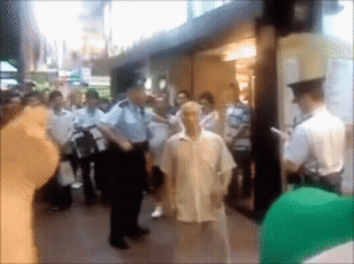 A Blurry Picture Of A Group Of People Standing Outside A Building GIF
