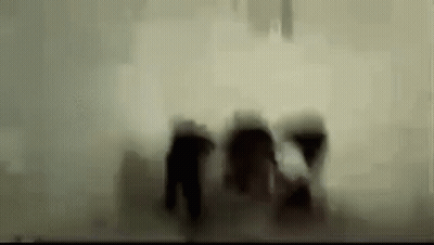 A Blurry Picture Of A Group Of People Walking In The Dark . GIF