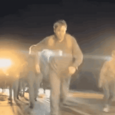A Blurry Picture Of A Man Carrying A Person In A Wheelchair At Night . GIF