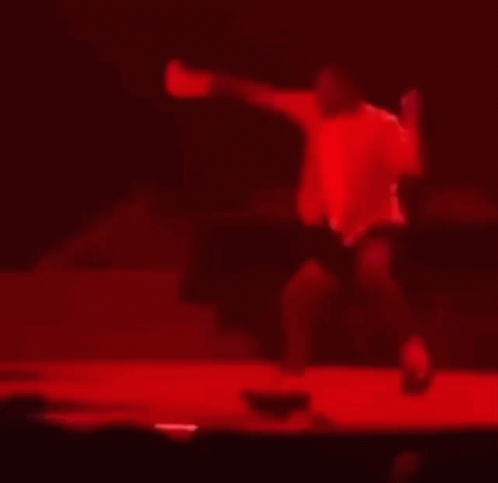 A Blurry Picture Of A Man Dancing On A Stage In A Dark Room . GIF