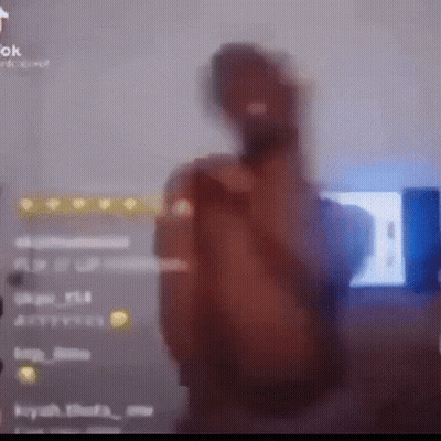 A Blurry Picture Of A Man Holding A Microphone In Front Of A Tv Screen GIF