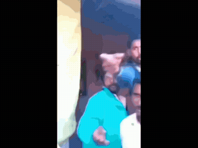 A Blurry Picture Of A Man In A Blue Shirt Pointing At Something GIF