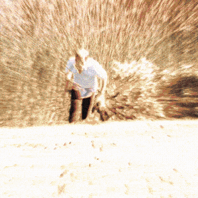 A Blurry Picture Of A Man In A Cowboy Hat Standing In The Sand GIF