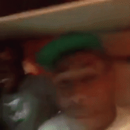 A Blurry Picture Of A Man In A Green Hat . GIF