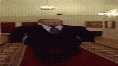 A Blurry Picture Of A Man In A Suit And Tie Walking Down A Red Carpet . GIF