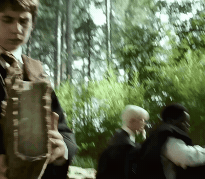 A Blurry Picture Of A Man In A Suit And Tie Walking In A Forest GIF