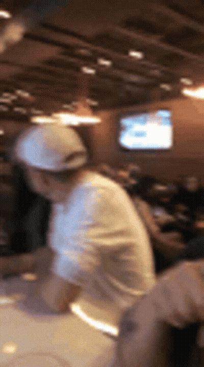 A Blurry Picture Of A Man In A White Hat Making Pizza GIF