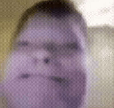 A Blurry Picture Of A Man 'S Face With A Purple Background . GIF