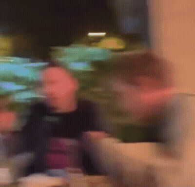 A Blurry Picture Of A Man Sitting At A Table In A Restaurant Eating Food . GIF