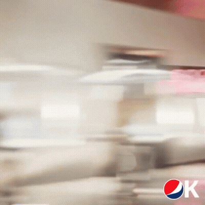 A Blurry Picture Of A Man Sitting At A Table With A Pepsi Logo GIF