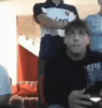 A Blurry Picture Of A Man Sitting In A Chair Holding A Remote Control . GIF