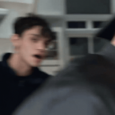 A Blurry Picture Of A Man Standing In A Kitchen Talking To Another Man . GIF