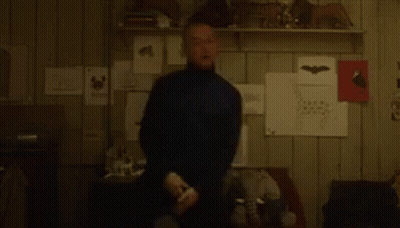 A Blurry Picture Of A Man Standing In A Room With A Shelf Full Of Drawings . GIF
